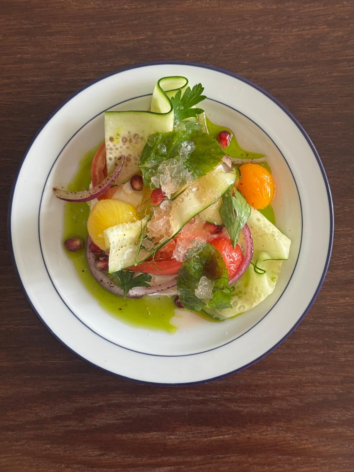 Cucumber and tomato salad with herbs, served on a white plate