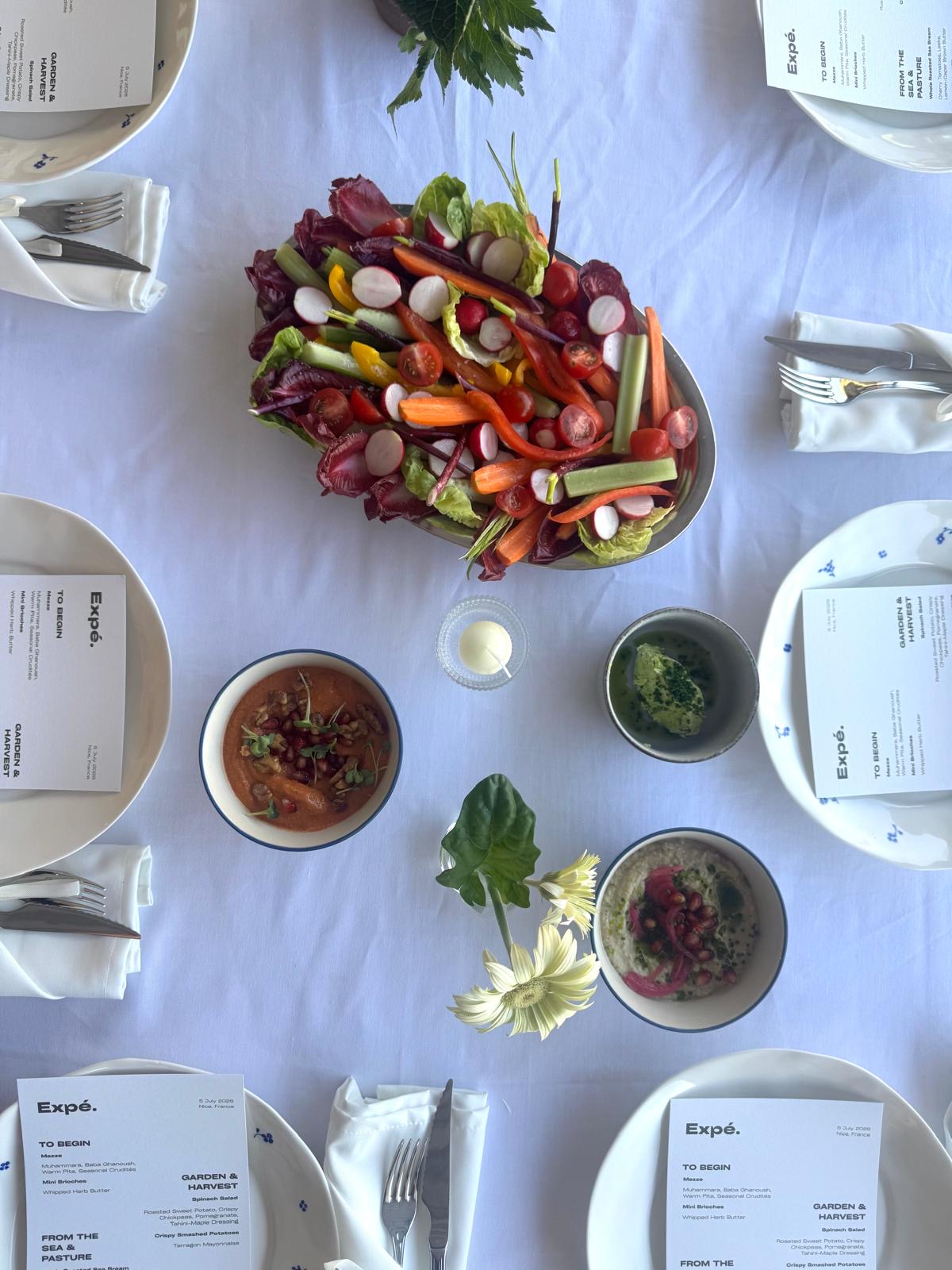 Garden dinner table set with seasonal dishes and printed menus