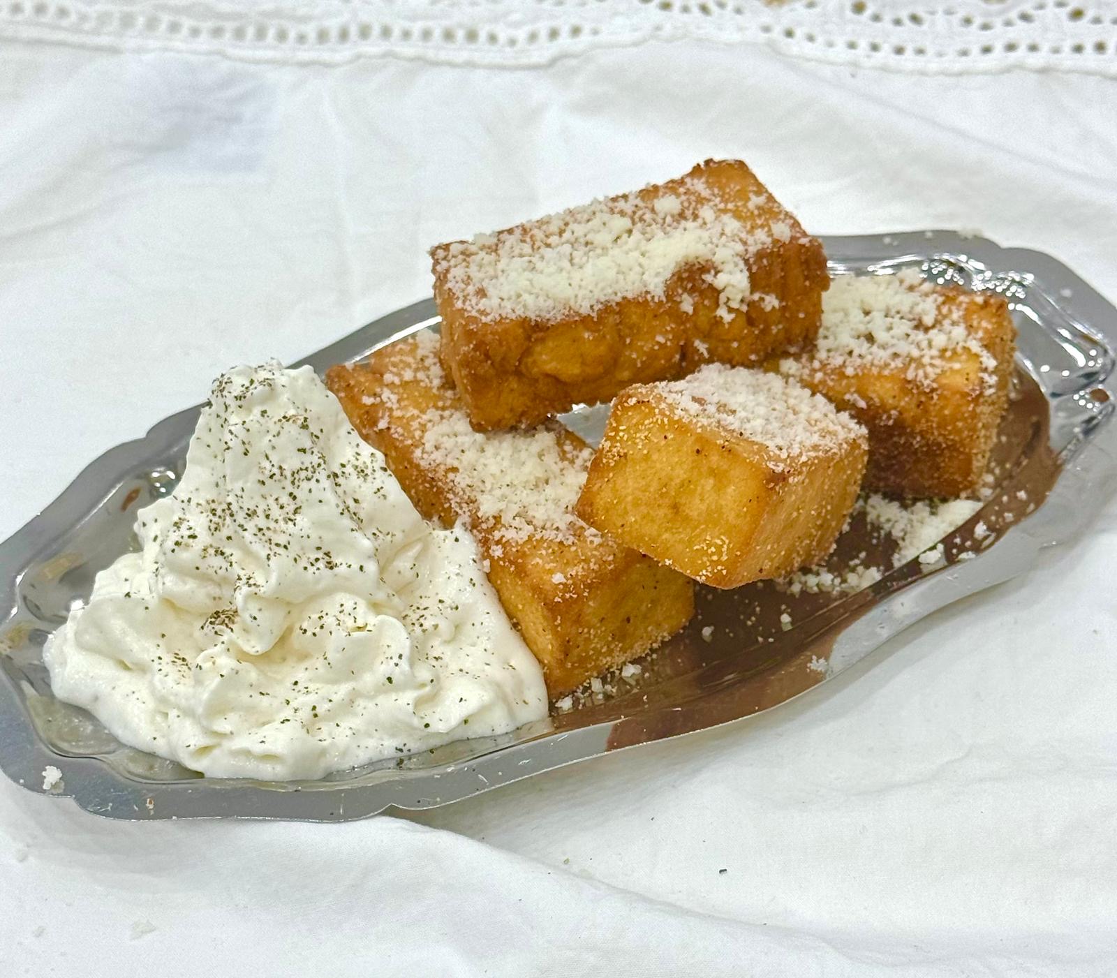 Golden brioche dessert with cream on a silver tray