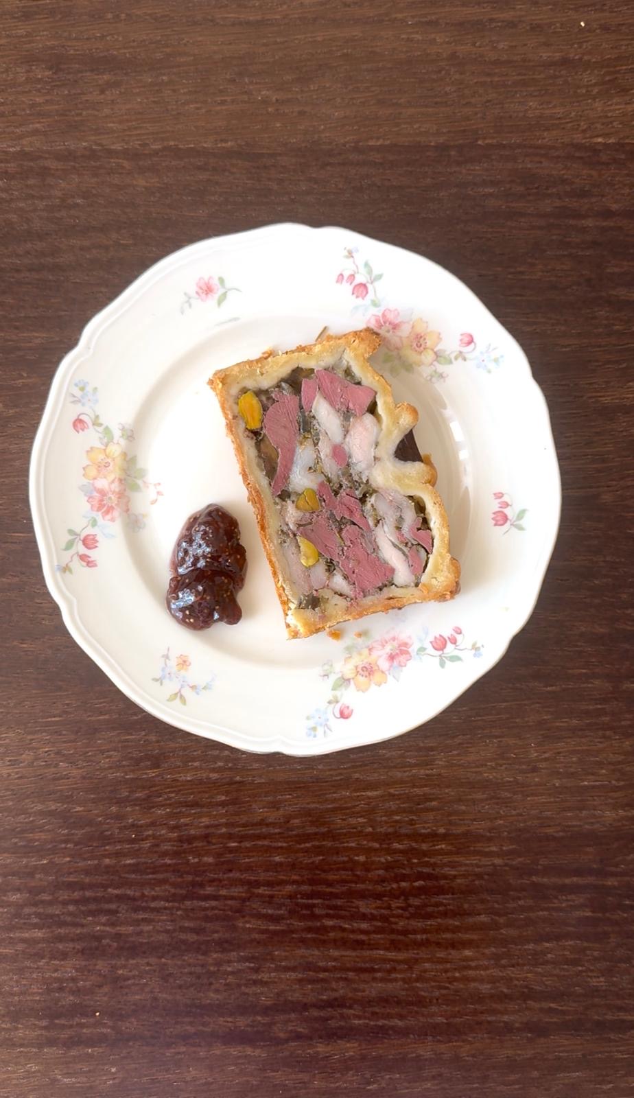 Slice of terrine en croûte served on a floral plate